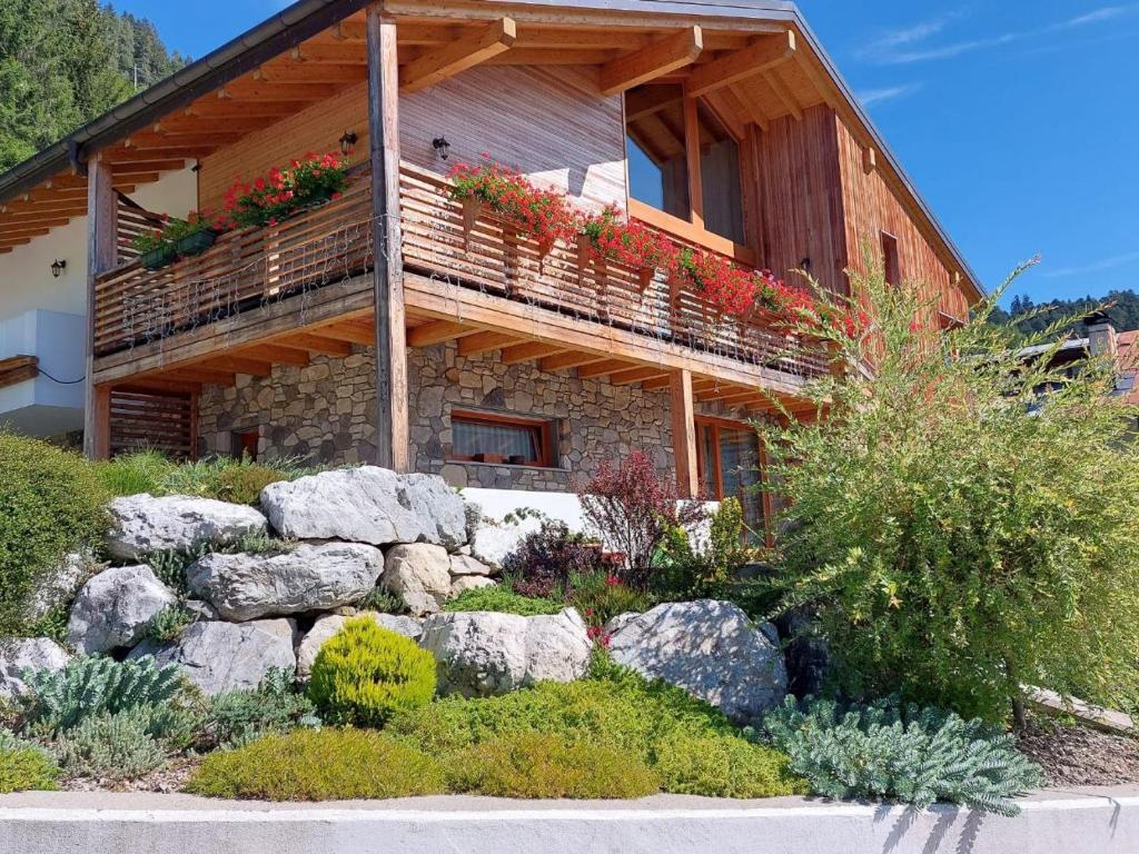 une maison en rondins avec des fleurs sur le balcon dans l'établissement Reggia al Sole, à Pieve di Cadore