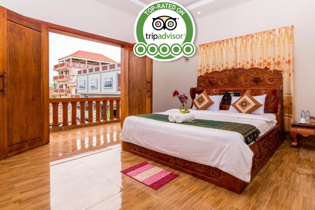 um quarto com uma cama grande e uma varanda em Aniza Angkor Villa em Siem Reap