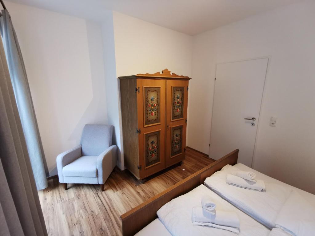 a bedroom with two beds and a chair and a cabinet at Apartments HAUS SCHÖN - Preise inclusive Pitztal Sommer Card in Jerzens