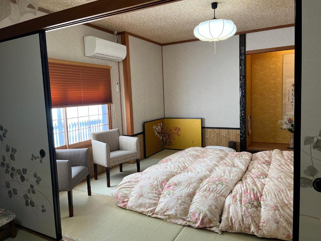 a bedroom with a bed and chairs and a window at Kyoto Ryokan Gion Sano in Kyoto