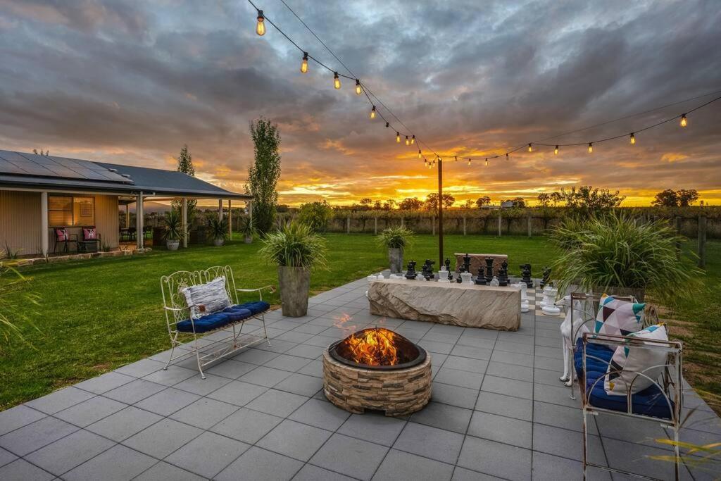 a patio with a fire pit and a table and chairs at 'Vineyard Cottage' A Golden Escape among the Vines in Eurunderee
