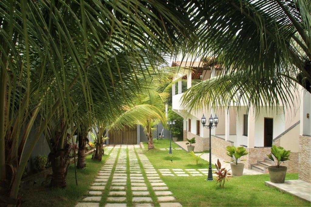 een binnenplaats met palmbomen en een loopbrug bij Residencial Jardim Imbassai 4 apt mobiliado com piscina in Mata de Sao Joao