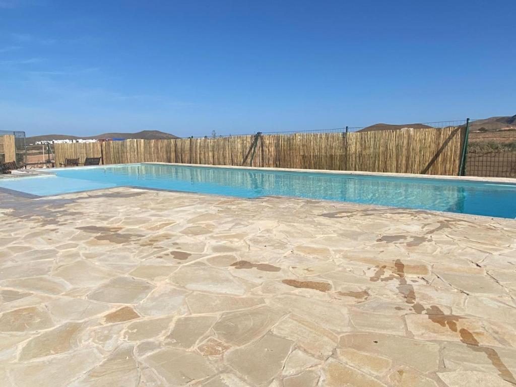 una piscina en un patio con una valla de madera en Villa Verano Apartamentos Compartidos Villaverde, en La Oliva