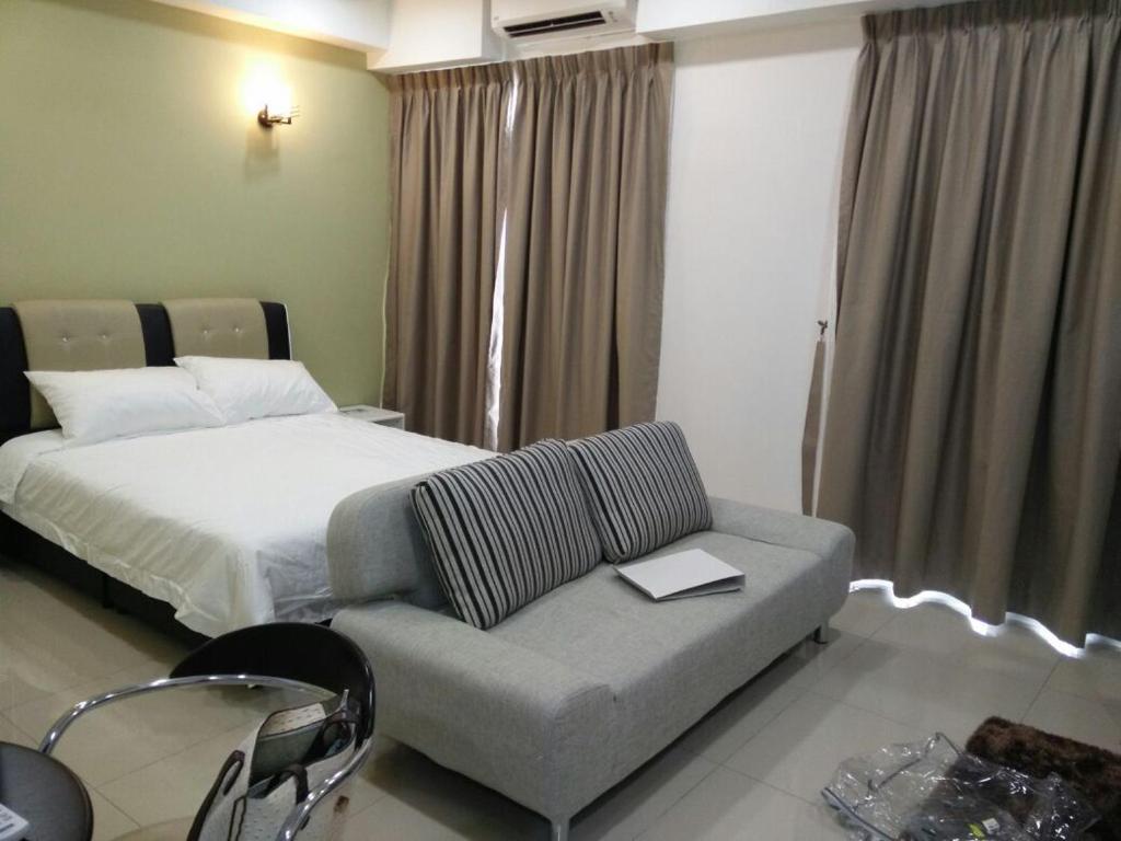 a bedroom with a bed and a couch with a laptop at DELUXE HOMESTAY @ D PERDANA in Kota Bharu