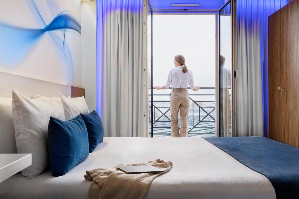 a woman looking out the window of a hotel room at Mercure Paris Gare du Nord in Paris