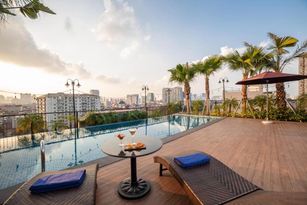 - une terrasse avec une table et des chaises au-dessus d'un bâtiment dans l'établissement FTE Ba Dinh Hotel, à Hanoï