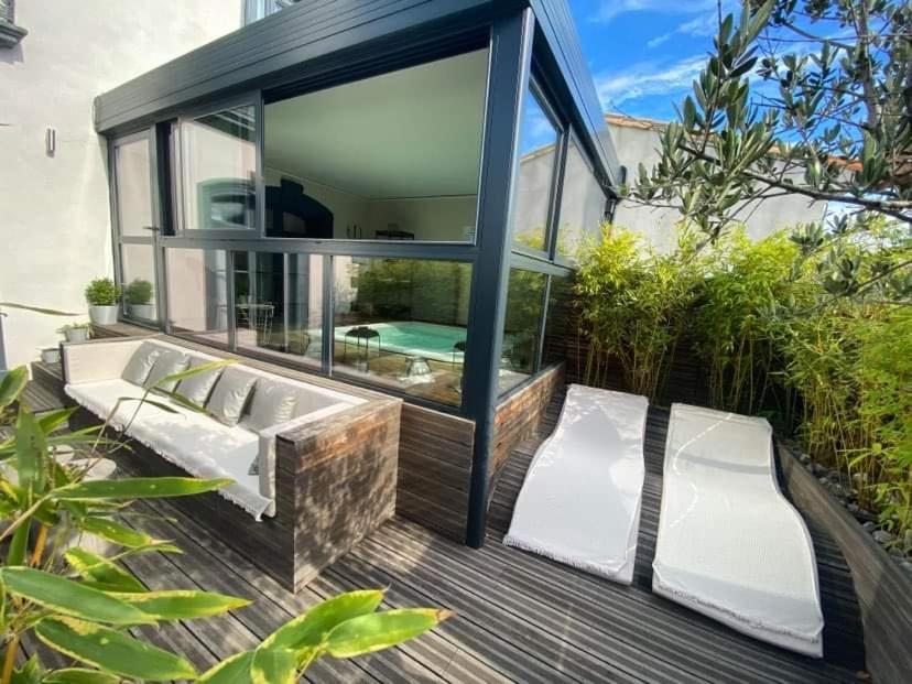 une maison en verre avec une piscine et deux chaises blanches dans l'établissement Demeure Terrisse La Résidence, à Marseillan