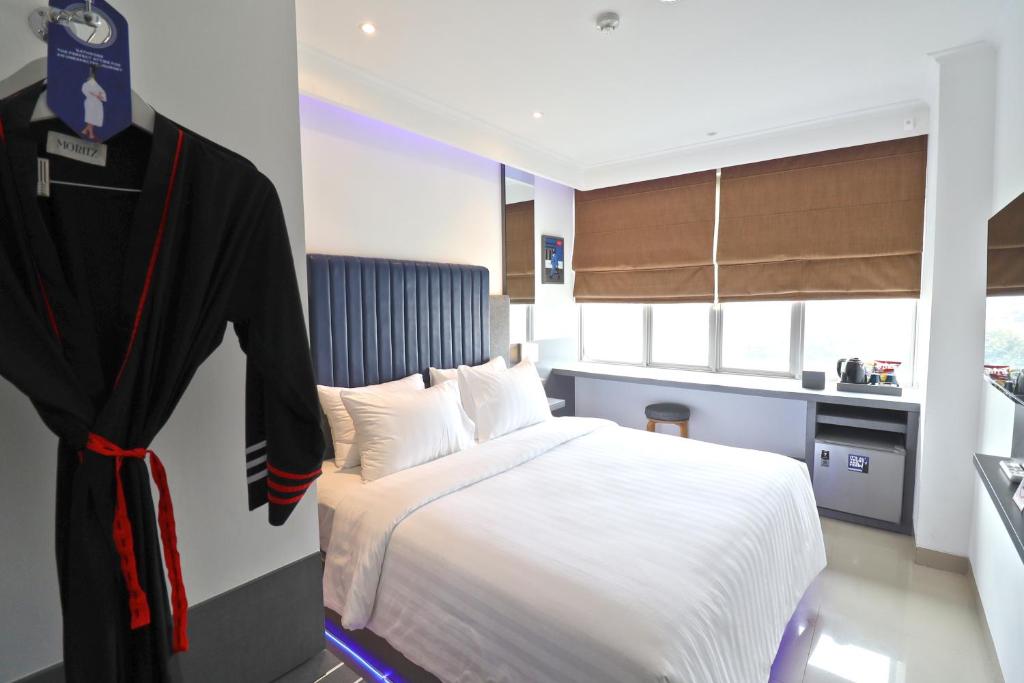 a bedroom with a bed and a robe hanging on a wall at Moritz Biz Gandaria in Jakarta
