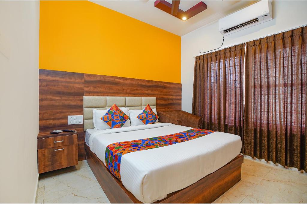 a bedroom with a bed and a yellow wall at FabHotel Greenwood Xpress in Bangalore