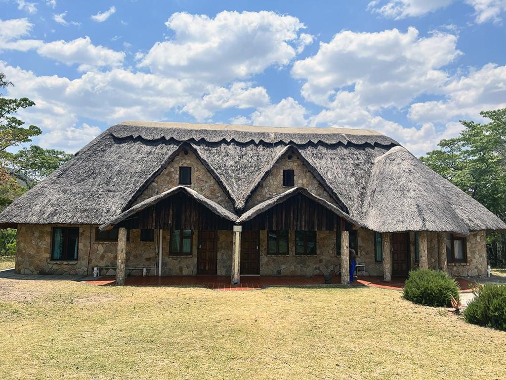 una casa con techo de paja en un campo en Lovely house on 4 hectares in John Galt Village - 2011 en Nyanga