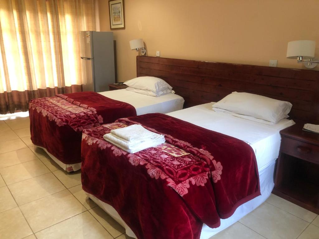 two beds in a hotel room with red sheets at A boutique lodge situated in a serene environment - 2029 in Harare