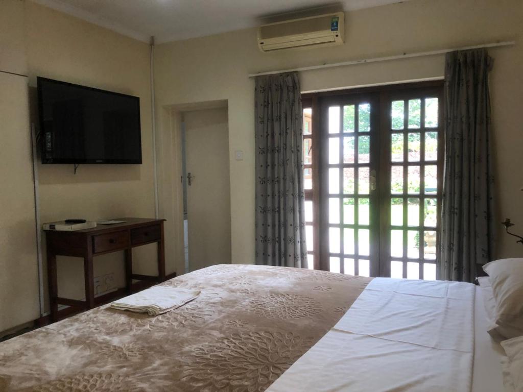 a bedroom with a bed and a flat screen tv at A boutique lodge situated in a serene environment - 2021 in Harare