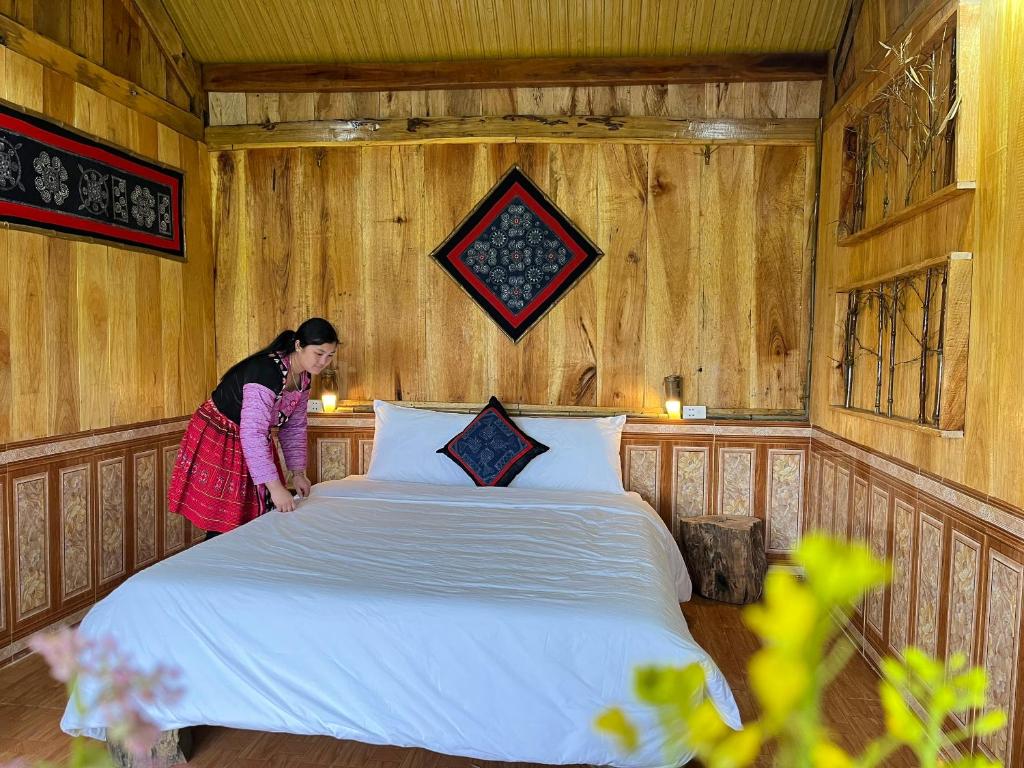 a woman standing next to a bed in a room at Hoa Phong homestay Moc Chau in Mộc Châu