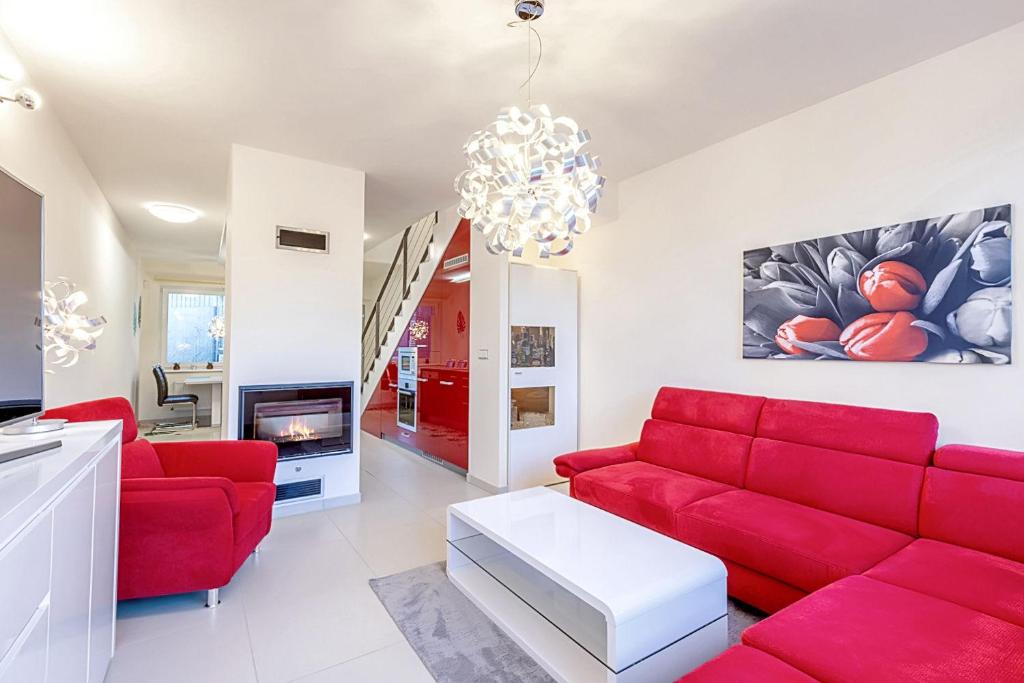 a living room with red furniture and a chandelier at Miky Apartmán Klínovec Garden in Loučná pod Klínovcem