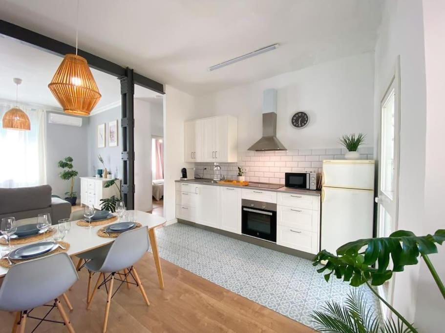 kuchnia z białymi szafkami, stołem i krzesłami w obiekcie Bright flat Rosaleda w Maladze