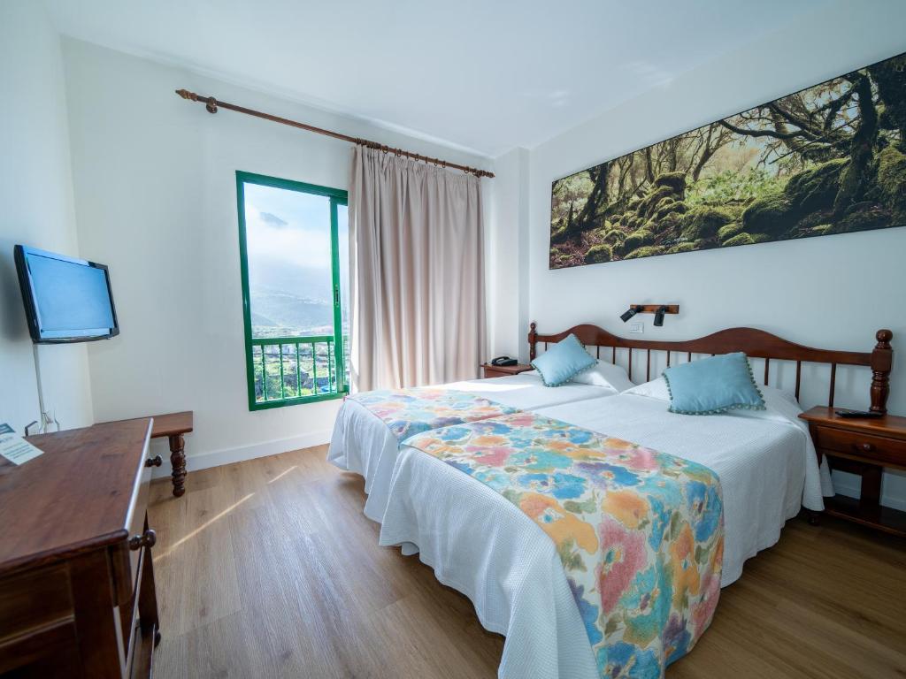 a bedroom with two beds and a desk and a television at Hotel Ida Inés in Frontera