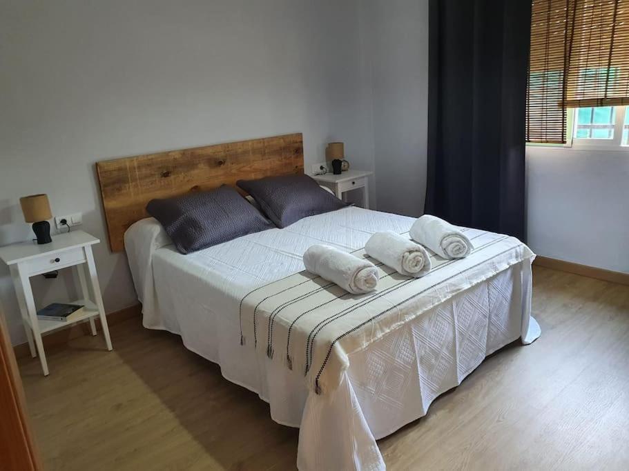 1 dormitorio con 1 cama grande con sábanas blancas y almohadas azules en Casa rural en Padul entre Sierra Nevada y la Costa, en Granada