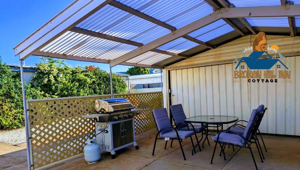un patio con mesa, sillas y parrilla en Broken Hill Inn Cottage, en Broken Hill