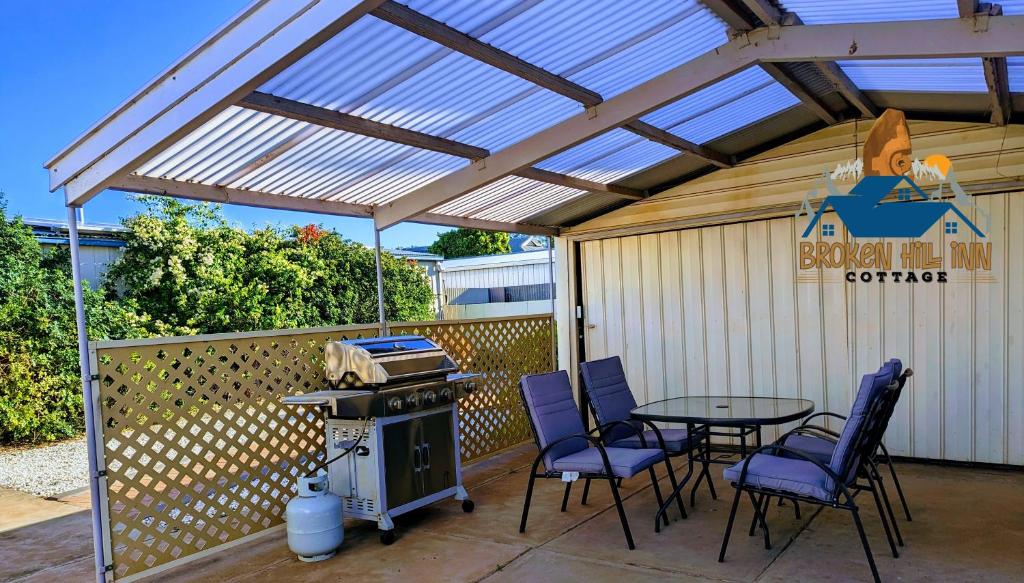 un patio con tavolo, sedie e griglia di Broken Hill Inn Cottage a Broken Hill