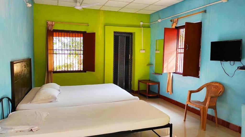 a room with two beds and a tv and a chair at Estuarine Village Resort Bhitarkanika 
