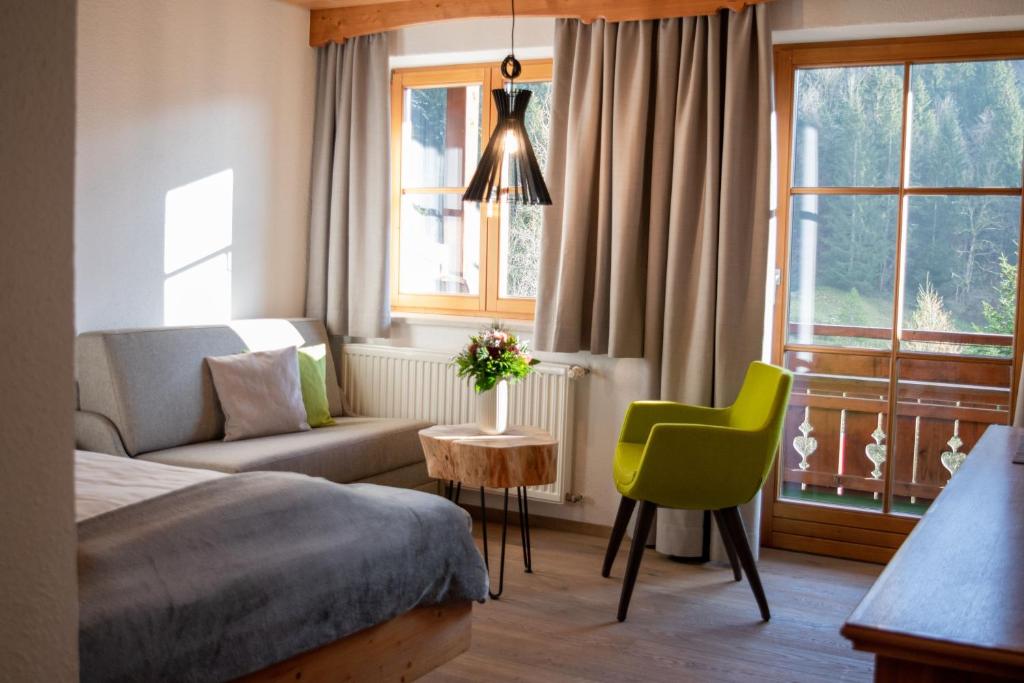 a bedroom with a bed and a couch and a chair at Hotel Bad Rain mit Oberstaufen PlusGolf in Oberstaufen