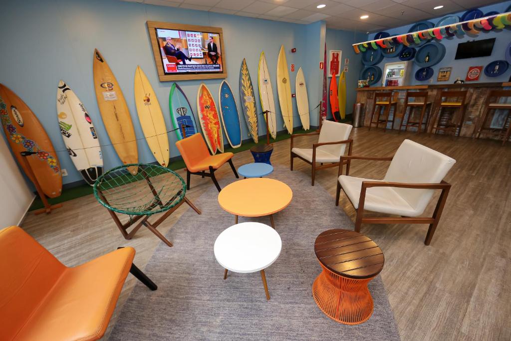 um quarto com cadeiras e mesas e pranchas de surf na parede em Delphin Surf Hotel no Guarujá