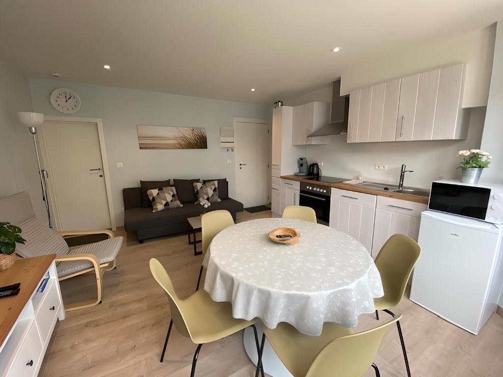 a kitchen and a living room with a table and chairs at 1 slaapkamer logie met extra zetelbed in leefruimte in Middelkerke