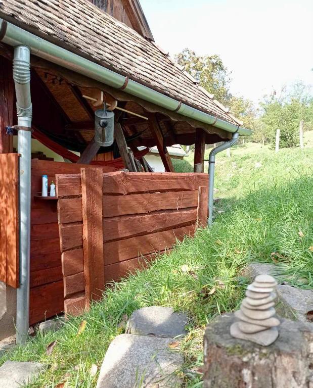 a wooden building with a porch and a stone stack at Nature Lodge Csesztve in Csesztve