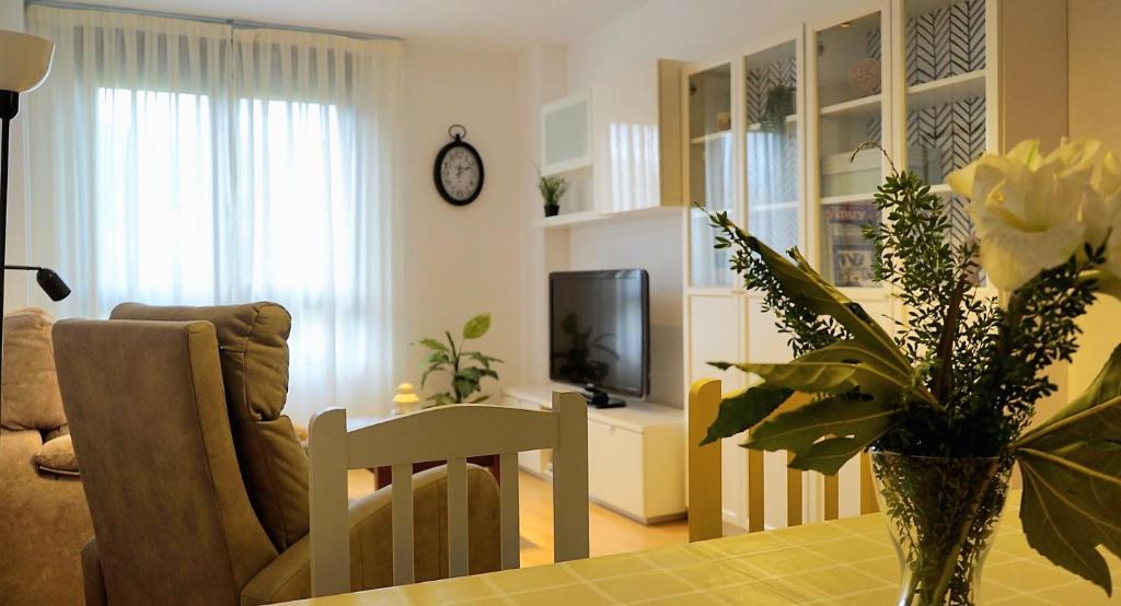 un salon avec une table et un vase de fleurs dans l'établissement Apartamento Estelas de Cantabria, à Los Corrales de Buelna