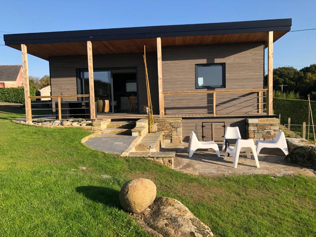 une maison avec deux chaises blanches devant dans l'établissement La Canopee, à Tonquédec