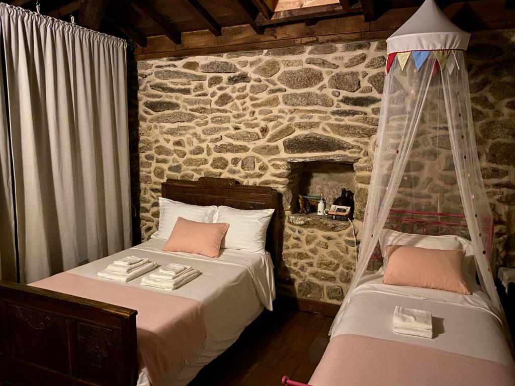 een slaapkamer met 2 bedden en een stenen muur bij Casa Garcia - Chaves in Chaves