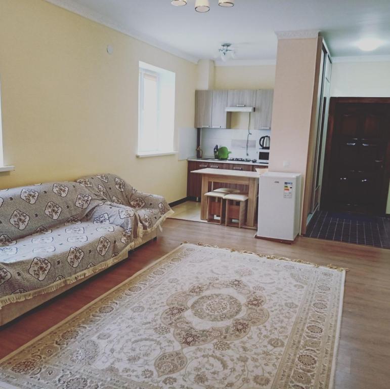a living room with a couch and a kitchen at Гостевой дом Самурук in Atyraū