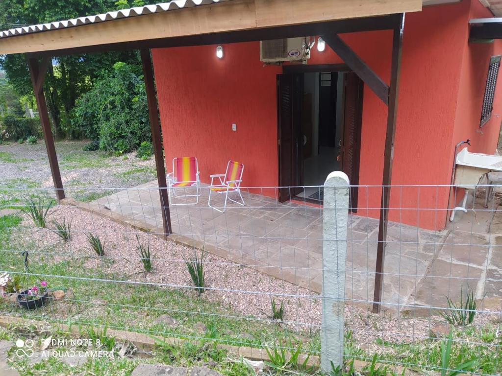 ein rotes Haus mit zwei Stühlen davor in der Unterkunft Casa Hermosa in Igrejinha