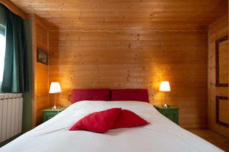 um quarto com uma cama branca e 2 almofadas vermelhas em casa Balto em Passo del Tonale