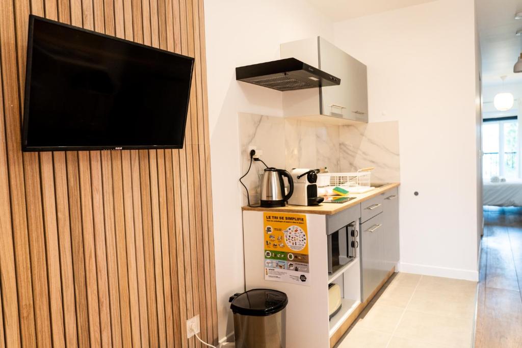 a kitchen with a tv hanging on a wall at Magnifique T2 centre ville dernier étage avec balcon in Valence