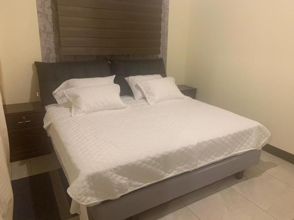 Una cama con sábanas blancas y almohadas en un dormitorio en Hermoso departamento cerca de todo, en Guayaquil