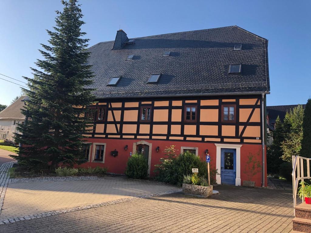 ein Haus mit einem Baum davor in der Unterkunft Ferienwohnung im Erzgebirge in Großhartmannsdorf