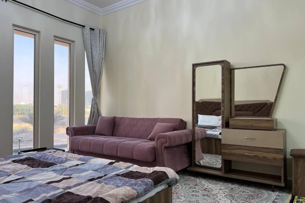 a bedroom with a purple couch and a mirror at Cozy 1 Bed in Sports City in Dubai