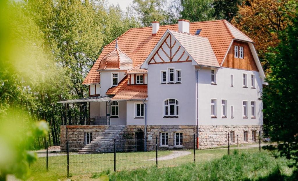 une grande maison blanche avec un toit orange dans l'établissement Sonnenblick, à Polanica-Zdrój