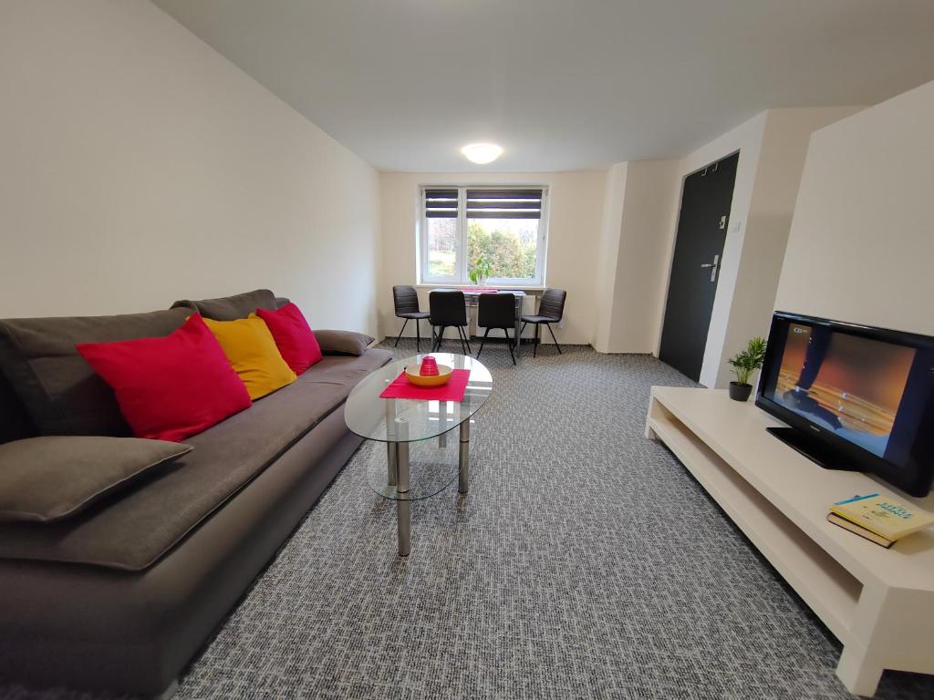 a living room with a couch and a table and a tv at Apartments Merci in Ostrava