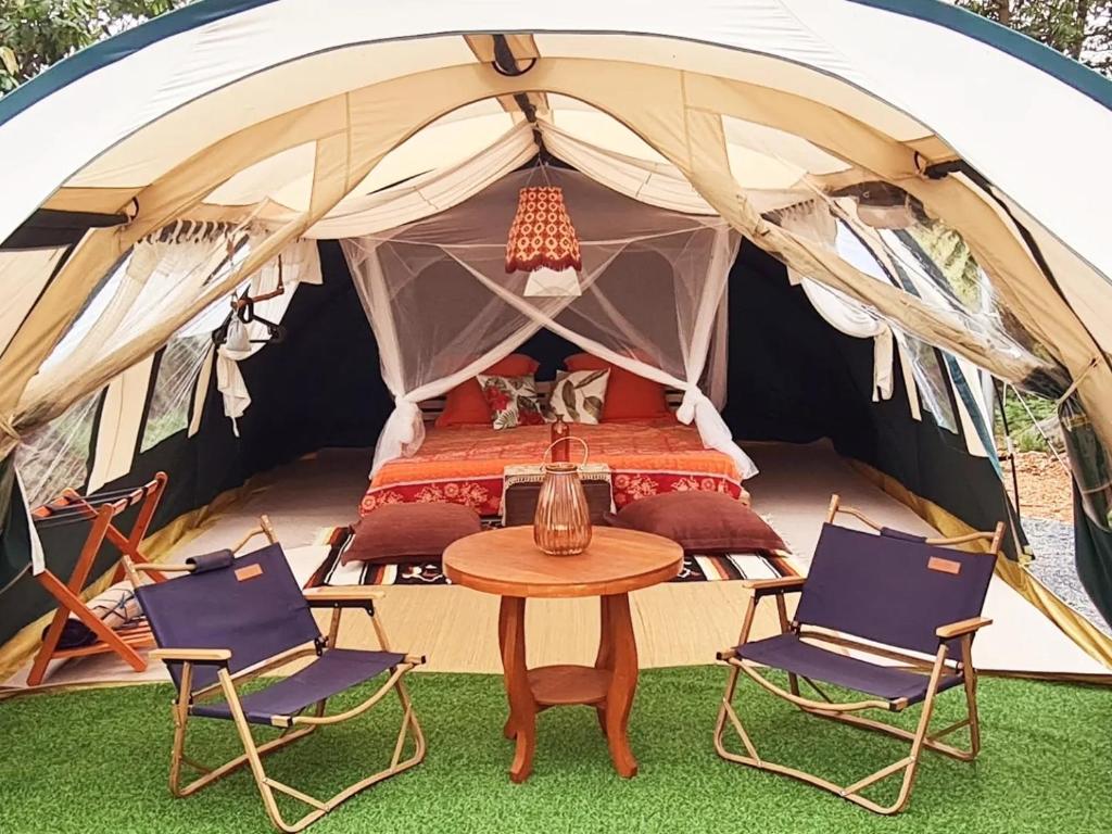 Ban Nong TakhainにあるVilla Noina Glampingのテント(ベッド1台、椅子2脚、テーブル付)