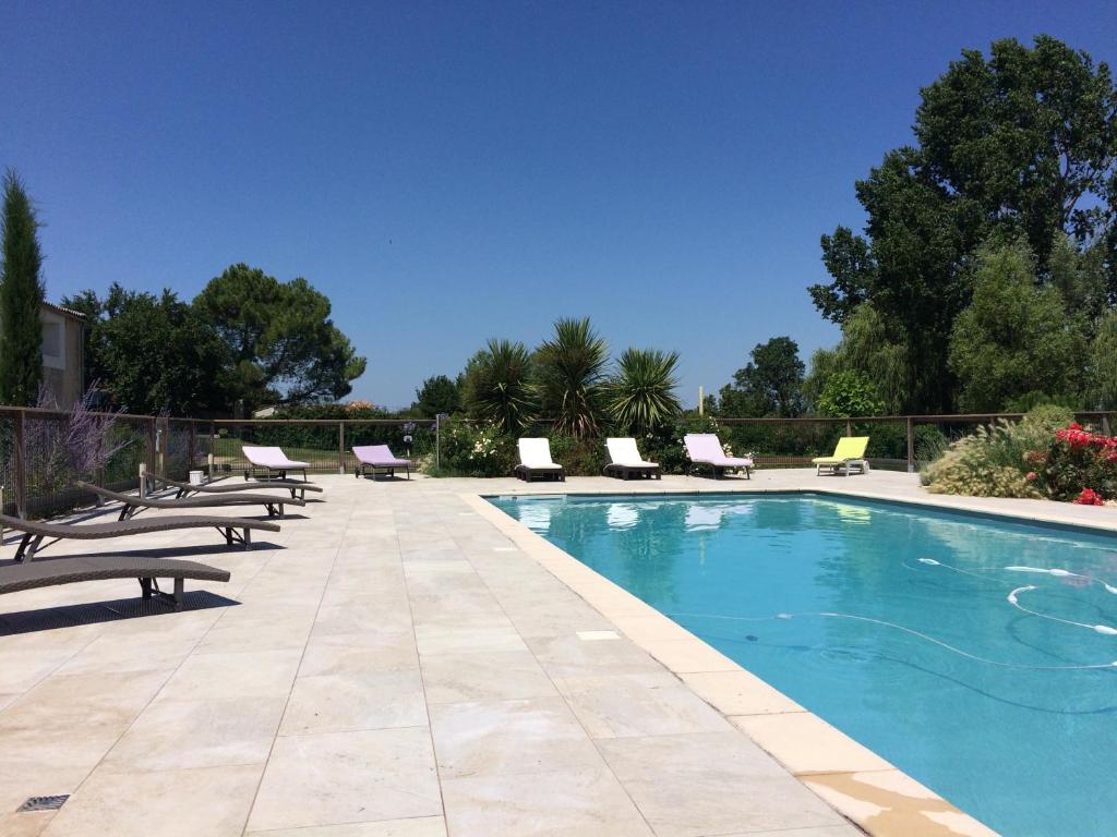 "Le gite du Petit Guilhem" Près Bordeaux Maison classée 4étoiles Meublé Tourisme piscine parc étang في Anglade: مسبح حوله كراسي وكراسي جلوس