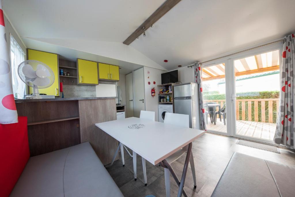 une cuisine avec une table blanche et des chaises dans l'établissement le 934 des charmettes, aux Mathes