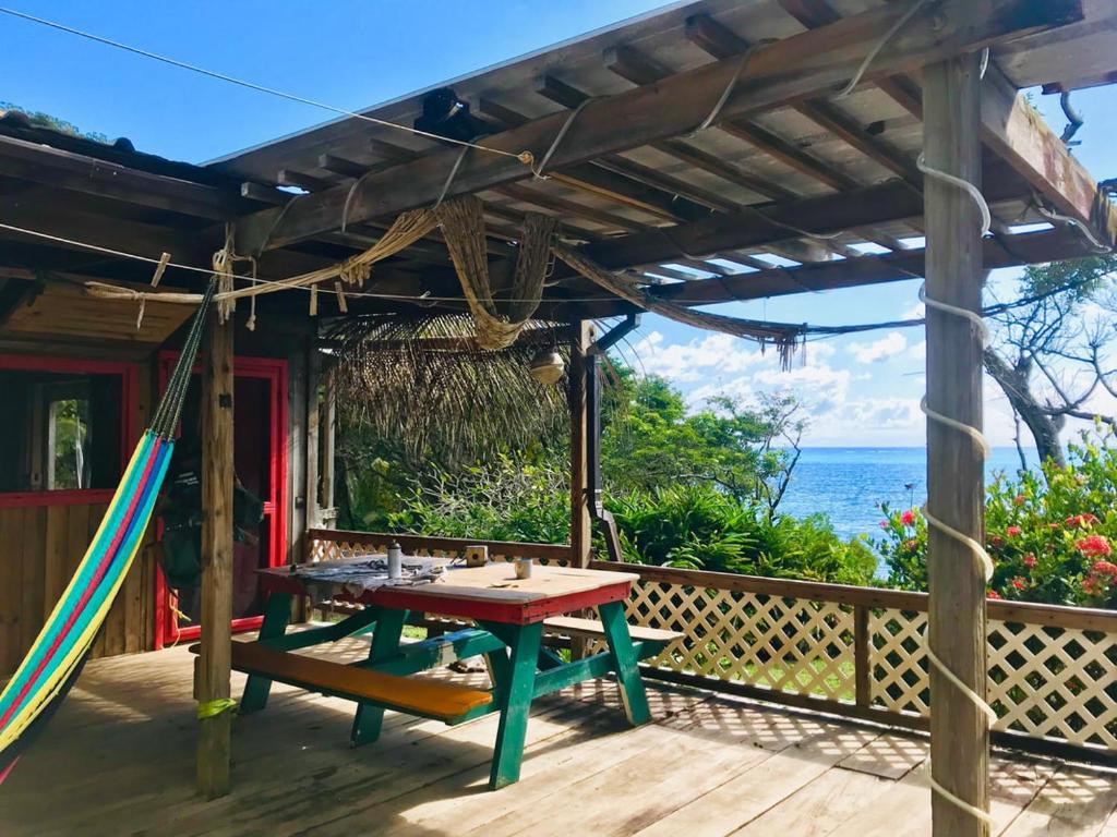 una terraza de madera con una mesa de picnic y una hamaca en Guanaja Backpackers Hostel, en Guanaja