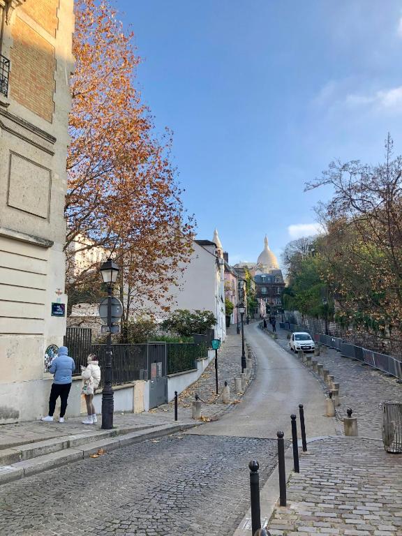 une femme et un enfant marchant dans une rue pavée dans l'établissement Rare appartement d'architecte en haut de Montmartre, à Paris