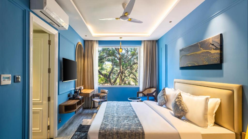 Renest Calangute Goa في كالانغيُت: غرفة نوم زرقاء مع سرير ومكتب