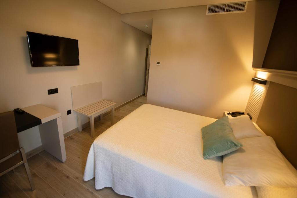 a small room with a bed and a television at Hotel Diufain in Conil de la Frontera