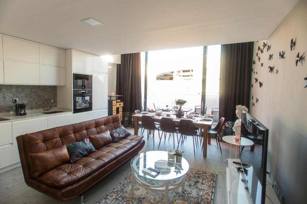 a living room with a brown leather couch and a table at Birds Apartments in Porto