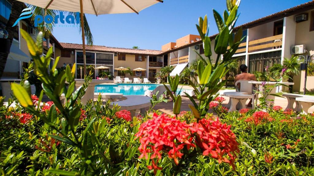 un complexe avec une piscine et quelques fleurs dans l'établissement Apart Hotel Portal Do Atlântico - Portal Hotéis, à Porto Seguro