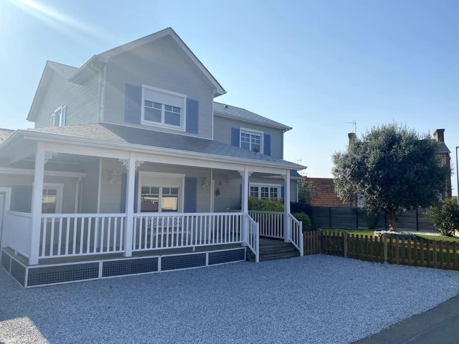 a white house with a porch and a fence at grande villa familiale in Saint-Pair-sur-Mer